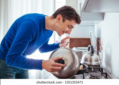 Young Man Sniffing Food From The Pan