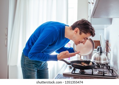 Young Man Sniffing Food From The Pan