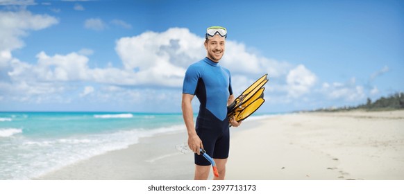 Young man with snorkeling equipment standing on a sandy beach  - Powered by Shutterstock