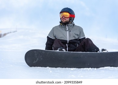 Young Man Snowboarding On The Slopes Of A Ski Resort.