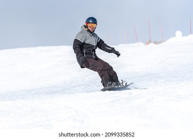 Young Man Snowboarding On The Slopes Of A Ski Resort.