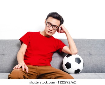 Young Man Soccer Fan Crying Face After Watching Football Match On Tv While Sitting On Grey Sofa And Wearing Red Shirt Short Sleeve.