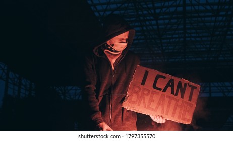 Young man solitary street protests stands with sign I Can't Breathe on cardboard, lights up with signal flare in hand background of industrial night. I Can't Breathe protests in USA, Europe. Freedom - Powered by Shutterstock