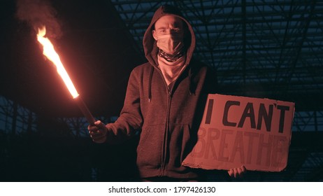 Young man solitary street protests stands with sign I Can't Breathe on cardboard, lights up with signal flare in hand background of industrial night. I Can't Breathe protests in USA, Europe. Freedom - Powered by Shutterstock