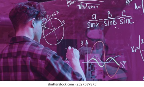 Young man solves mathematical equations on blackboard. Media. Young man solves complex equations on transparent board. Genius writes equations on blackboard in neon light