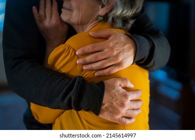 A Young Man, A Son Carefully Hugs His Beloved Grandmother, Supports And Helps An Elderly Woman In Retirement, His Grandparent. Young Male And Female Elderly Hands With Wrinkles Closeup. 