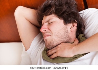 Young Man With Sore Throat Lying In His Bed