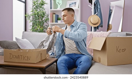 Young man sorting clothes into donation box in a cozy living room.
