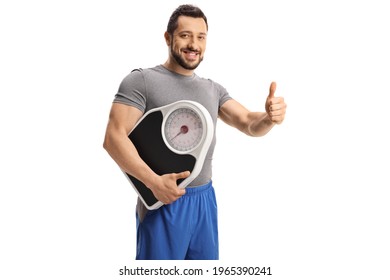 Young Man In Sport Clothes Holding A Measuring Scale And Gesturing  Thumb Up Sign Isolated On White Background