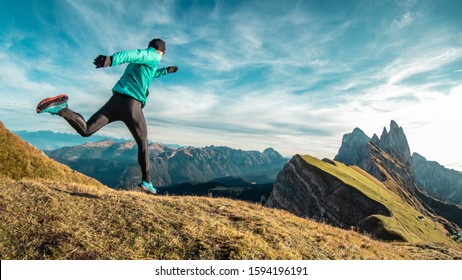 Young Man In Sport Trail Clothes Running On Seceda Mountain Peak At Sunrise. Puez Odle, Trentino, Dolomites, Italy.