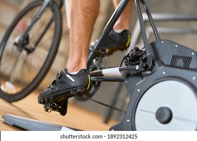 Young man in sports shoes riding stationery bike