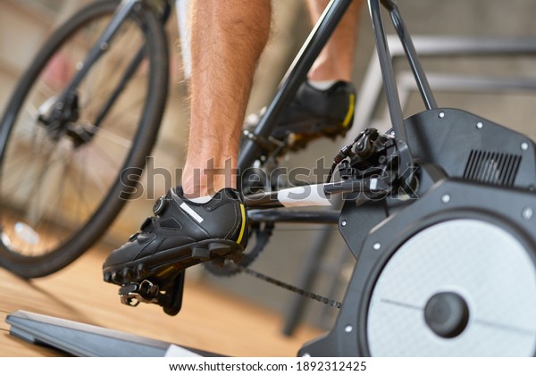 Young man in\
sports shoes riding stationery\
bike