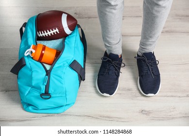 Young Man In Sportswear And Bag With Gym Equipment Indoors