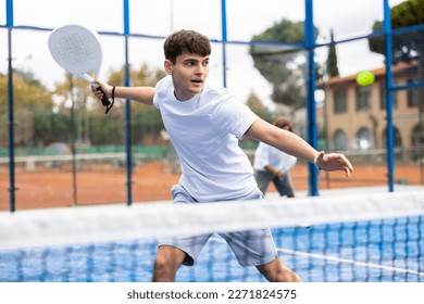 Young man in sportswear playing padel tennis match during training on court - Powered by Shutterstock