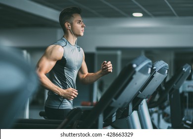 Young man in sportswear running on treadmill at gym
