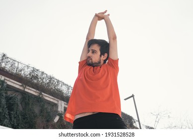 Young Man In Sportswear Stretching Both Arms Above Head