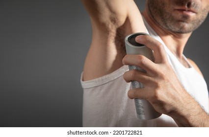 Young Man Spraying Deodorant On Armpit.