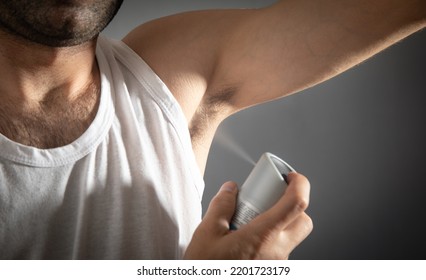 Young Man Spraying Deodorant On Armpit.