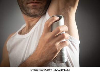 Young Man Spraying Deodorant On Armpit.