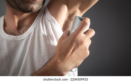 Young Man Spraying Deodorant On Armpit.