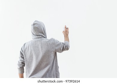 Young man spraying paint at the concrete wall with copy space