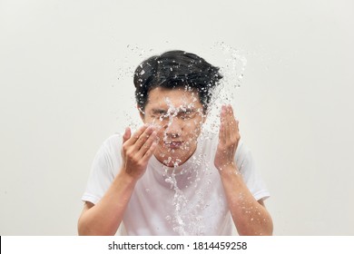 Young Man Spraying Water On His Face Over White Background