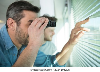 young man is spying his neighbours with binoculars - Shutterstock ID 2124196205
