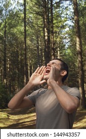 Young Man Standing Alone In Woods And Yelling