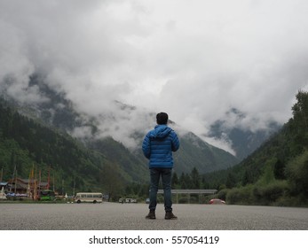 Young man standing back to the camera in the cloudy valley scene. 