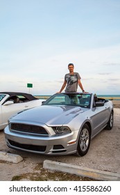 Young man standing in a brand new Ford Mustang convertible parked near Key West, Florida, USA. - Shutterstock ID 415586260