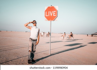 Young Man Standing By The Dream Sign In The Middle Of A Desert At The Burning Man Art Festival. Sign To Live Your Life.