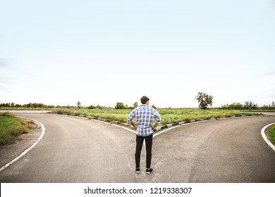 Young Man Standing At Crossroads. Concept Of Choice