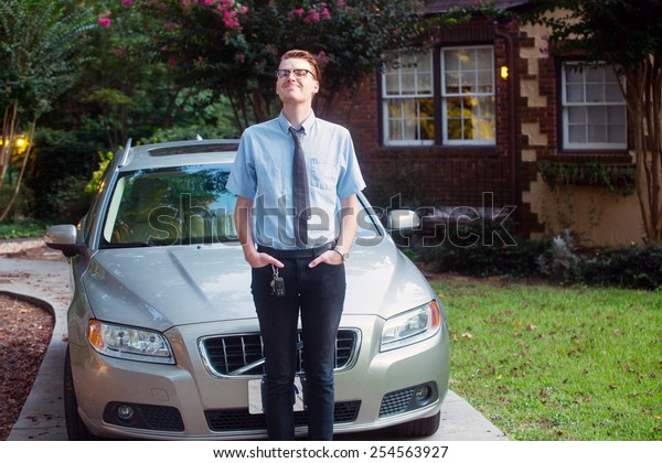 young man standing in front of car outside in front\
of new home