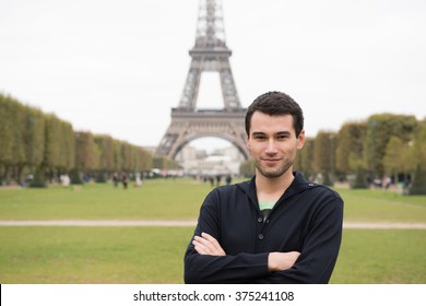 Young man standing in front of Eiffel Tower in Paris, France, wearing black clothes