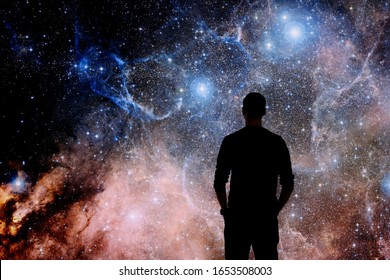 Young man standing in front of the huge picture of star nebula. Man in the universe. Man watching the space. Meaning of life. Visiting the observatory. Elements of the image furnished by NASA. 