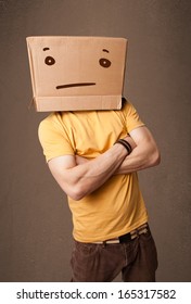 Young Man Standing And Gesturing With A Cardboard Box On His Head With Straight Face