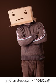 Young Man Standing And Gesturing With A Cardboard Box On His Head With Straight Face