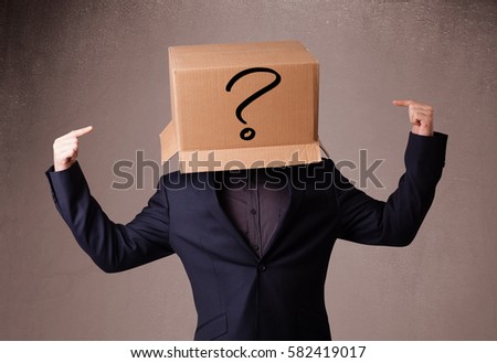 Young man standing and gesturing with a cardboard box on his head with question mark