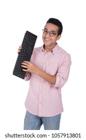 Young man standing and holding a keyboard only without computer acting like typing, isolated on a white background.