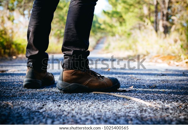 Young man standing in the middle of a divided\
highway in the\
wilderness.