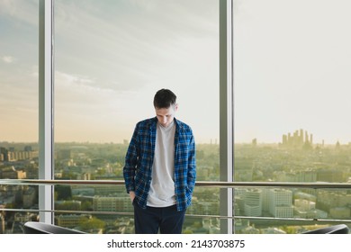 Young Man Standing Near Panorama Window Looking At The City, Home Interior