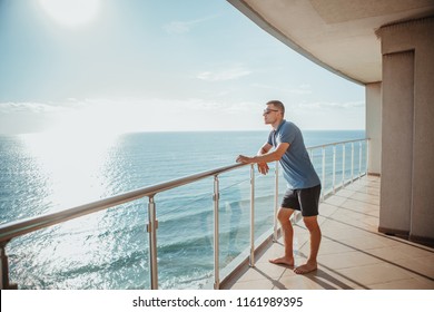 Young man standing on the balcony looking at the sea. Relaxation minute concept - Powered by Shutterstock