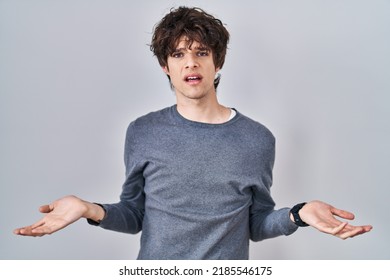 Young Man Standing Over Isolated Background Clueless And Confused With Open Arms, No Idea Concept. 