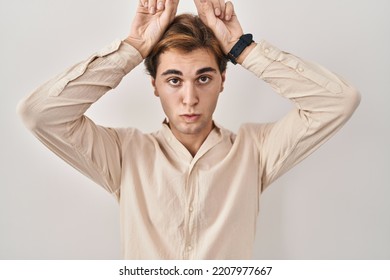 Young Man Standing Over Isolated Background Doing Funny Gesture With Finger Over Head As Bull Horns 