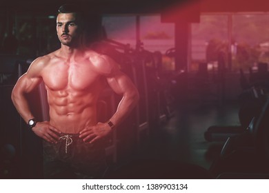 Young Man Standing Strong In The Gym And Flexing Muscles - Muscular Athletic Bodybuilder Fitness Model Posing After Exercises - Powered by Shutterstock