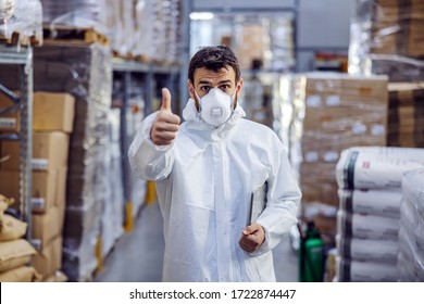 Young man standing in warehouse full of food and showing thumbs up. All warehouse is disinfected from corona virus/ covid-19. - Shutterstock ID 1722874447