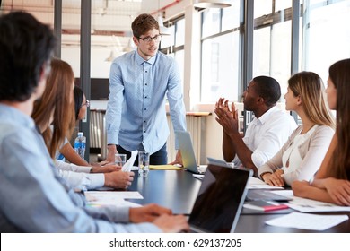 Young man stands addressing colleagues at business meeting - Shutterstock ID 629137205