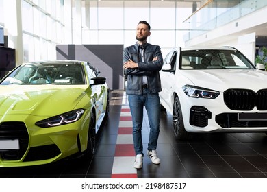 A Young Man Stands Between Two Sports Cars In A Car Dealership