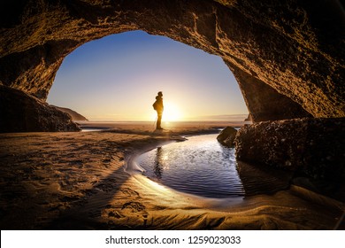 Young man stands at a cave exit. A person deep thinking at the exit of a cave. Beautiful landscape formation of a cave in New Zealand - Powered by Shutterstock