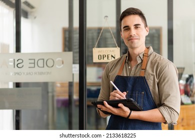 A Young Man Stands In Front Of A Storefront With An Open Sign Behind The Concept Of Opening A Food And Beverage Outlet.